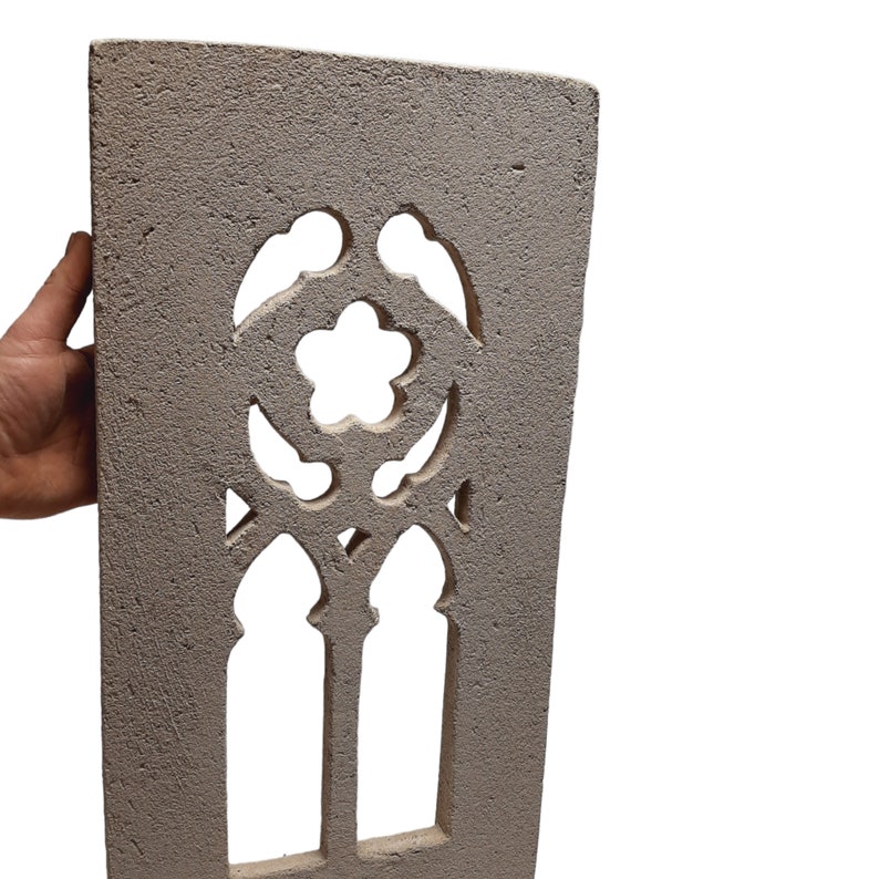 May include: A gray concrete wall panel with a decorative cutout design. The cutout features a stylized flower with two arched openings below.