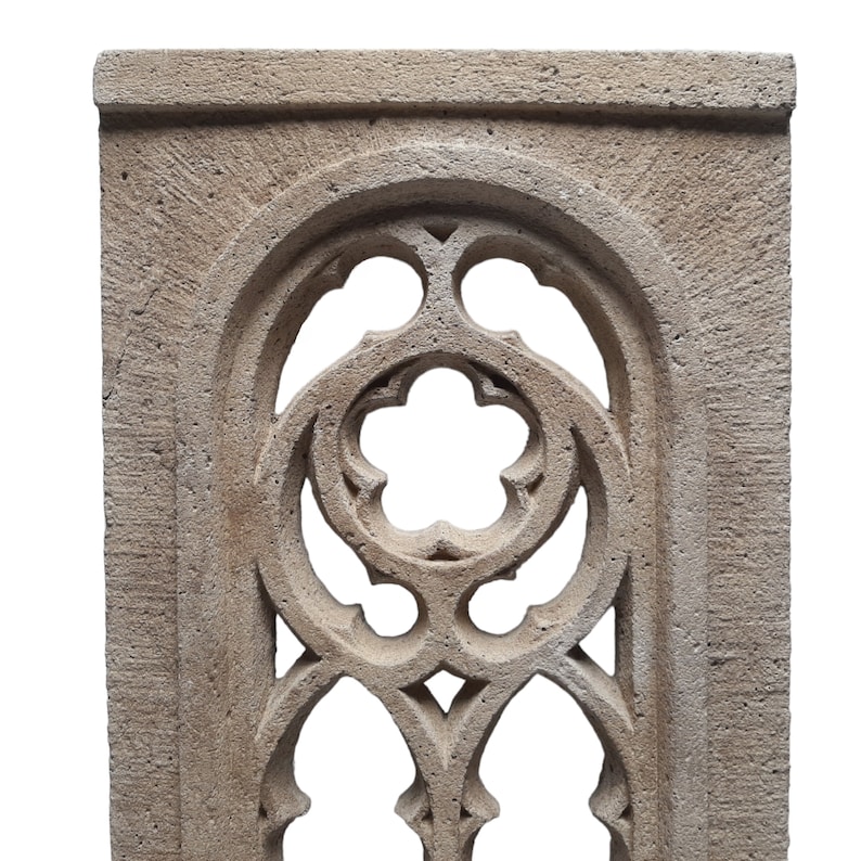 May include: A decorative stone archway with a detailed, intricate design. The archway is made of a light gray stone and has a rough, textured surface.