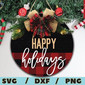 Puede incluir: Un letrero redondo de madera con fondo negro y un patr&oacute;n de cuadros rojos y negros. El letrero dice "Felices Fiestas" en letras doradas.