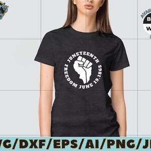 May include: A black t-shirt with a white circle graphic featuring a raised fist and the text "Juneteenth Freedom June 19, 1865".