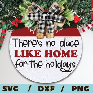 Puede incluir: Un letrero redondo de madera blanco y rojo con el texto "There's no place LIKE HOME for the holidays" en letras negras. Un lazo a cuadros blanco y negro con una cinta de arpillera marr&oacute;n est&aacute; en la parte superior del letrero.