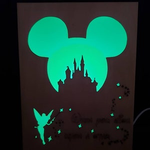 May include: A wooden glow-in-the-dark nightlight featuring a silhouette of Mickey Mouse's head with Cinderella's castle inside. The nightlight also features a fairy with a wand and the text "When you wish upon a star".