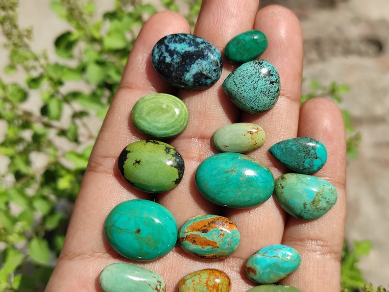 May include: A collection of turquoise cabochons in various shades of green and blue. The stones are smooth and polished, with some showing natural veining and inclusions.