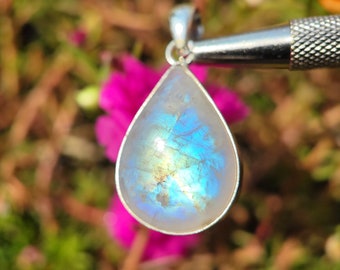 May include: A teardrop-shaped pendant with a silver setting and a blue and white iridescent moonstone.