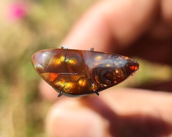 May include: A brown, orange, and green agate cabochon with a swirling pattern. The cabochon is set in a silver bezel and is ready to be made into jewelry.