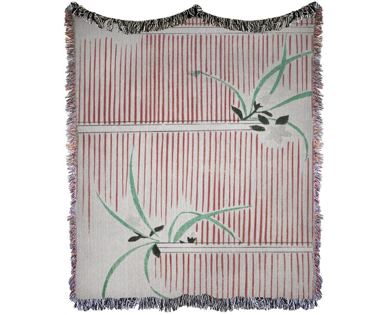 Pode incluir: Uma manta tecida com um padr&atilde;o de listras vermelhas e brancas e um design floral verde. A manta tem uma borda de franjas.