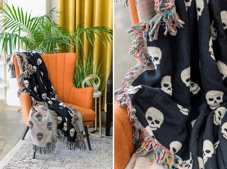 May include: A black and white throw blanket with a skull pattern. The blanket has a colourful fringe border and is draped over an orange armchair.