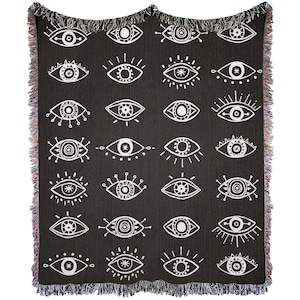 May include: Black woven throw blanket with a white eye pattern. The eyes are stylized and have different designs.