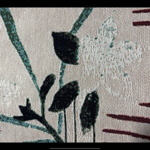 Pode incluir: Close-up de um tecido bege com um padr&atilde;o floral preto e verde. O tecido tem um design tecido texturizado e apresenta um padr&atilde;o repetitivo de folhas e flores.