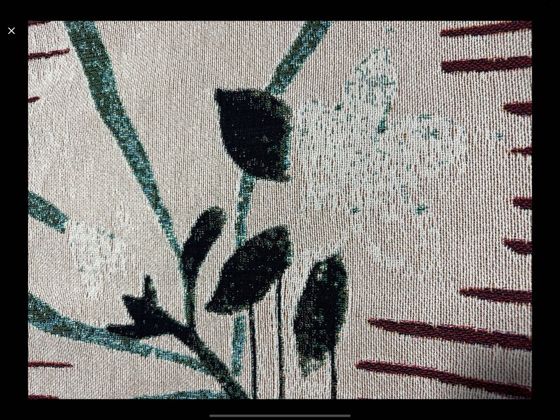 Pode incluir: Close-up de um tecido bege com um padr&atilde;o floral preto e verde. O tecido tem um design tecido texturizado e apresenta um padr&atilde;o repetitivo de folhas e flores.