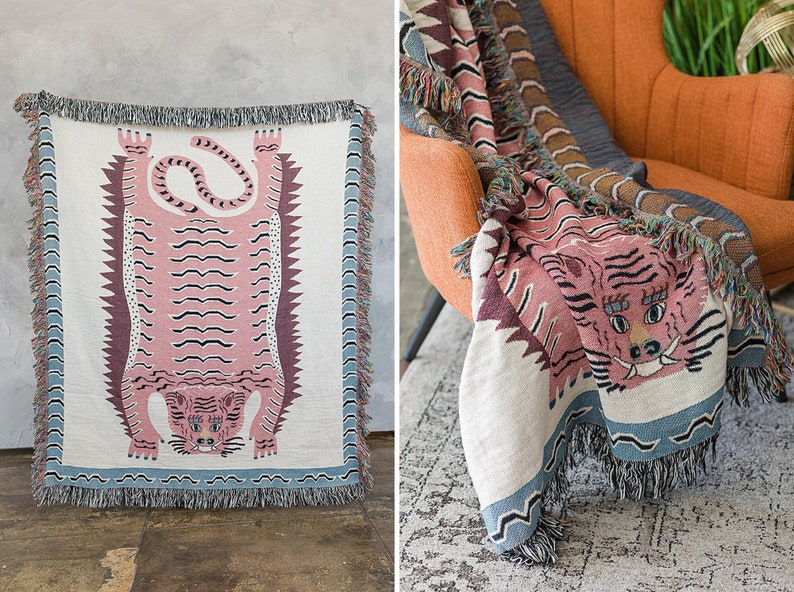 May include: A pink and white woven throw blanket with a tiger design. The blanket has a fringe border and is draped over a chair.