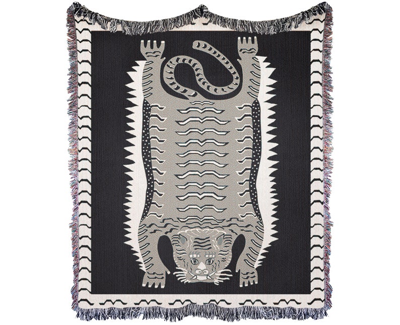 May include: A black and white woven throw blanket with a stylized tiger design. The tiger is facing up with its paws in the air. The blanket has a fringe border.