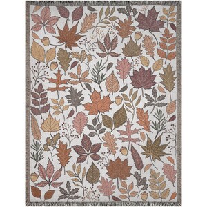 May include: A woven throw blanket featuring a repeating pattern of autumn leaves in shades of brown, orange, and pink on a cream background. The blanket has a fringed edge and is suitable for home decor.