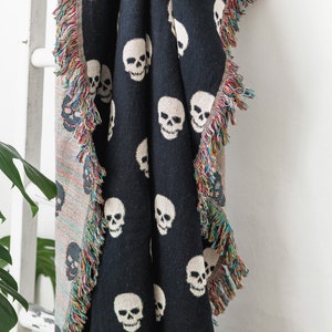 May include: Black throw blanket with a white skull pattern and fringe trim.
