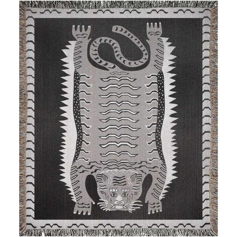 May include: A woven tapestry featuring a gray tiger with black stripes, lying on its back with its paws in the air. The tiger is on a black background with a white border.