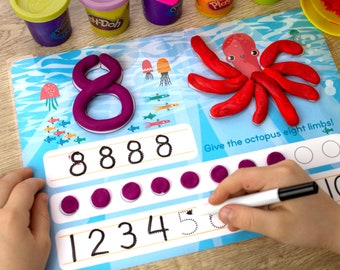 May include: A blue and white learning mat with a red octopus made of play dough. The mat has numbers 1-5 and 8 written on it. There are also several purple play dough circles on the mat. The text "Give the octopus eight limbs!" is written on the mat.
