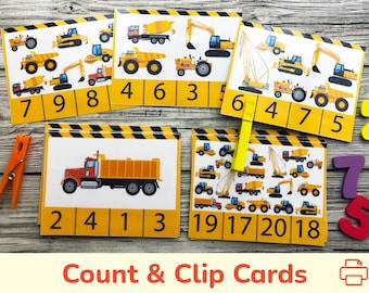 May include: Construction vehicle count and clip cards.  Yellow cards with images of construction vehicles and numbers.  A yellow clothespin is clipped to the card with the numbers 6, 4, 7, and 5.  The text "Count & Clip Cards" is printed below the cards.