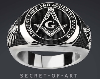 May include: A silver Masonic ring with a black enamel inlay featuring a compass and square with the letter "G" in the center. The ring is inscribed with the words "Ancient Free and Accepted Masons".
