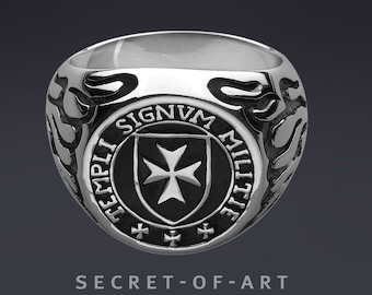 May include: A silver ring with a black enamel shield featuring a white cross and the inscription "TEMPLI SIGNVM MILITIE".