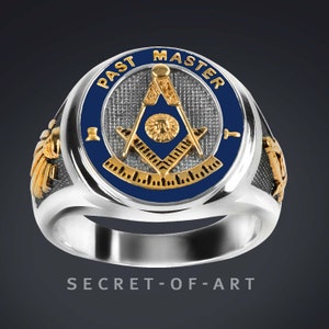 May include: A silver Masonic ring with a blue enamel inlay featuring a gold compass and square, surrounded by the words "Past Master". The ring has gold wings on either side.