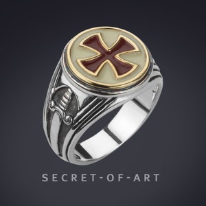 Könnte beinhalten: Ein silberner Ring mit einem roten Kreuz auf weißem Hintergrund. Der Ring hat eine goldene Einfassung und ein detailliertes Design auf der Band.