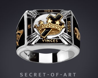 May include: A silver ring with black enamel and gold accents. The ring features a cross with a crown above it and the words "Hoc In Signo Vinces" around it.
