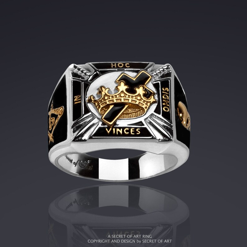 May include: A silver ring with a black enamel inlay featuring a gold crown, cross, and the text "HOC SIGNO VINCES".