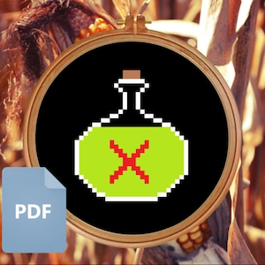 May include: A green and red pixelated potion bottle with a cork top in a black embroidery hoop.
