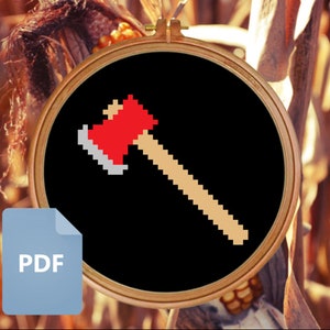 May include: A black and white pixel art design of a red axe with a wooden handle. The design is in a circular embroidery hoop.