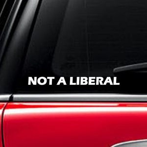 May include: A white vinyl decal with the text "NOT A LIBERAL" on a black car window.