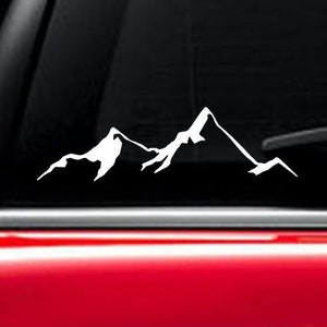 May include: A white mountain range silhouette decal for a car window. The decal is on a black car window.