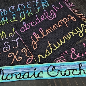 Peut inclure: Pièces de crochet noires avec des lettres et des symboles brodés aux couleurs de l'arc-en-ciel. L'alphabet est affiché en majuscules et en minuscules. Une bannière indique "Mosaic Crochet".