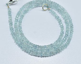 May include: A delicate aquamarine gemstone necklace. The necklace is composed of small, faceted, light blue beads strung together. It features a silver-colored clasp and a small gold-colored ring for closure. The beads are arranged in multiple strands.