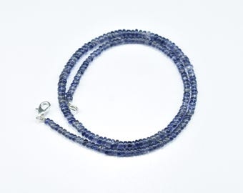 May include: A delicate necklace composed of small, round, dark blue beads. The necklace is strung together and has a silver-colored clasp. The beads are a deep, rich blue color, and the necklace is displayed against a white background.
