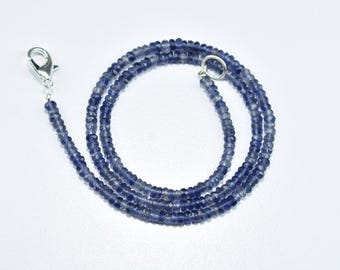 May include: A blue gemstone necklace made with small, faceted beads. The necklace is strung on a silver chain with a lobster clasp.
