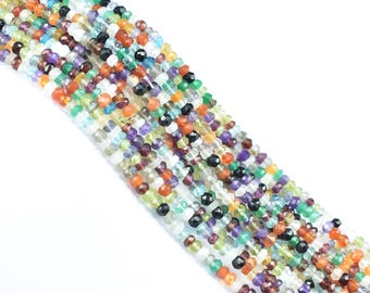 May include: Strands of colorful gemstone beads in various sizes and shapes. The beads are a mix of colors including green, orange, purple, black, and clear. The beads are strung together, creating a textured and vibrant appearance.