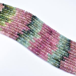 May include: A strand of multi-colored tourmaline beads. The beads are faceted and have a variety of shades of pink, green, and blue.