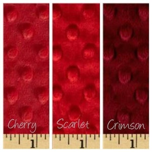 May include: Three fabric swatches in different shades of red: cherry, scarlet, and crimson. Each swatch has a textured, dotted pattern.