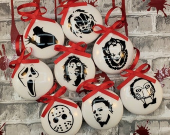 May include: Eight white Christmas ornaments with black and white images of horror movie characters. The characters include Freddy Krueger, Pennywise, Jason Voorhees, Michael Myers, Ghostface, Chucky, and Leatherface.