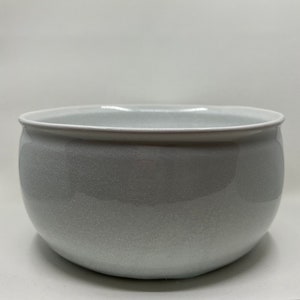May include: A white ceramic bowl with a slightly rounded shape and a speckled glaze.