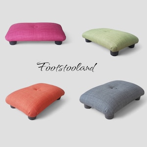 May include: Four different colored fabric footstools with a button tuft on top. The footstools are arranged in a square shape with the word "Footstooland" in the center.