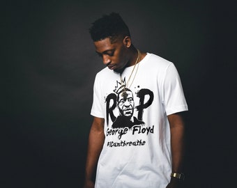 May include: A white t-shirt with a black and white graphic print of a man's face with the words "RIP George Floyd #CantBreathe".