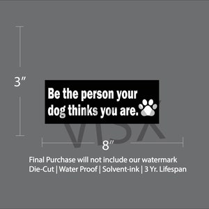 May include: Black and white sticker with the text "Be the person your dog thinks you are." and a paw print. The sticker is 3 inches tall and 8 inches wide.
