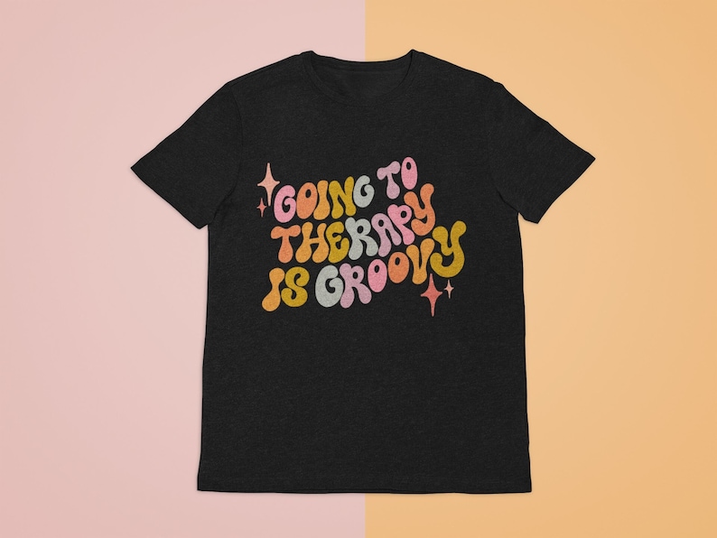 Puede incluir: Camiseta negra con un gr&aacute;fico retro de colores que dice "Going to Therapy is Groovy".