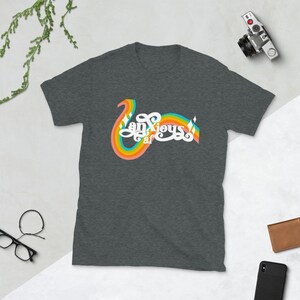 以下が含まれることがあります： レトロな虹のデザインで「Anxious af」の文字が入った濃いグレーのTシャツ。柔らかい素材でできており、普段着に適しています。デザインは虹のアーチと装飾的な要素が特徴です。