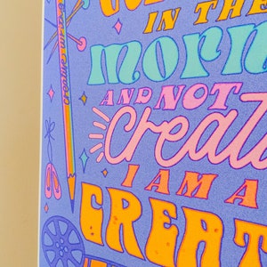 May include: A purple poster with colourful text that reads "I get creative in the morn and not crazy I am a great". The poster has a rainbow border and various colourful illustrations of creative tools, such as a pencil, scissors, and a film reel.