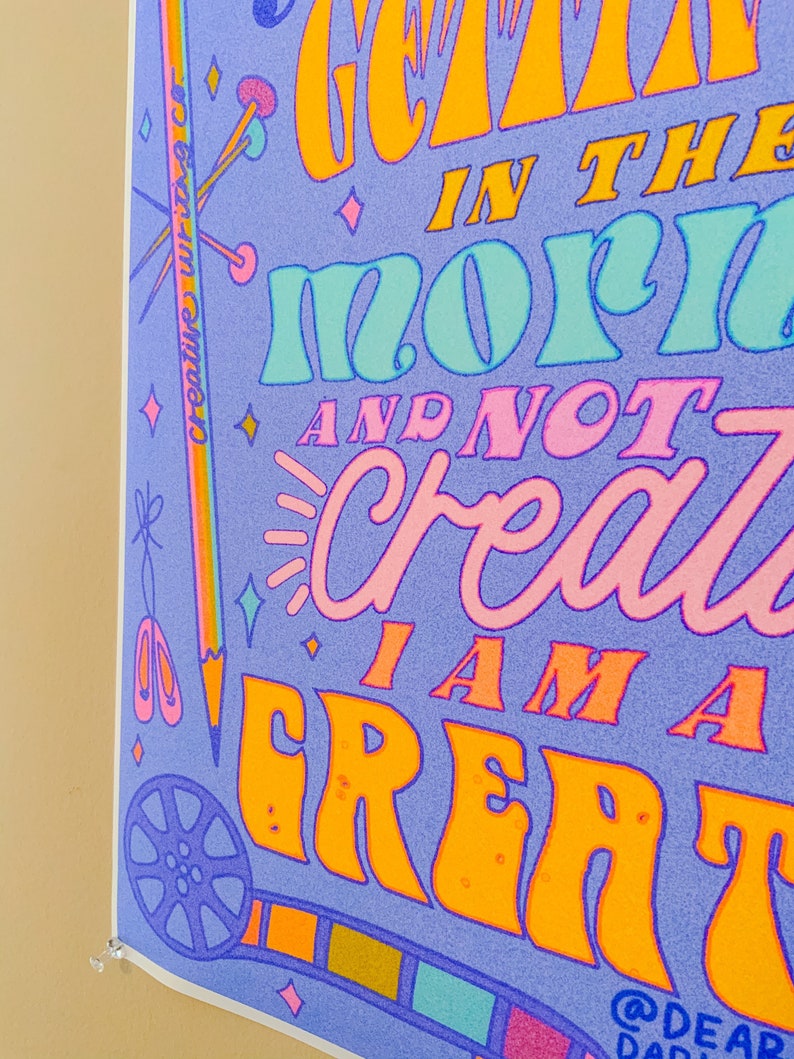 May include: A purple poster with colourful text that reads "I get creative in the morn and not crazy I am a great". The poster has a rainbow border and various colourful illustrations of creative tools, such as a pencil, scissors, and a film reel.