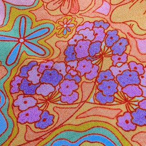 May include: Close-up of a fabric with a vibrant floral pattern. The design features large, stylized flowers in shades of orange, pink, and purple, outlined in red. The background has a mix of yellow, green, and blue wavy lines.