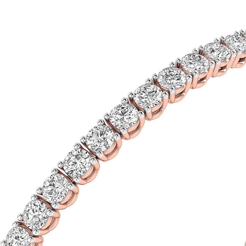 Puede incluir: Una pulsera de tenis de oro rosa con una serie de diamantes redondos con talla brillante. Los diamantes est&aacute;n engastados muy juntos, creando una l&iacute;nea continua de brillo. La pulsera se muestra sobre un fondo blanco.