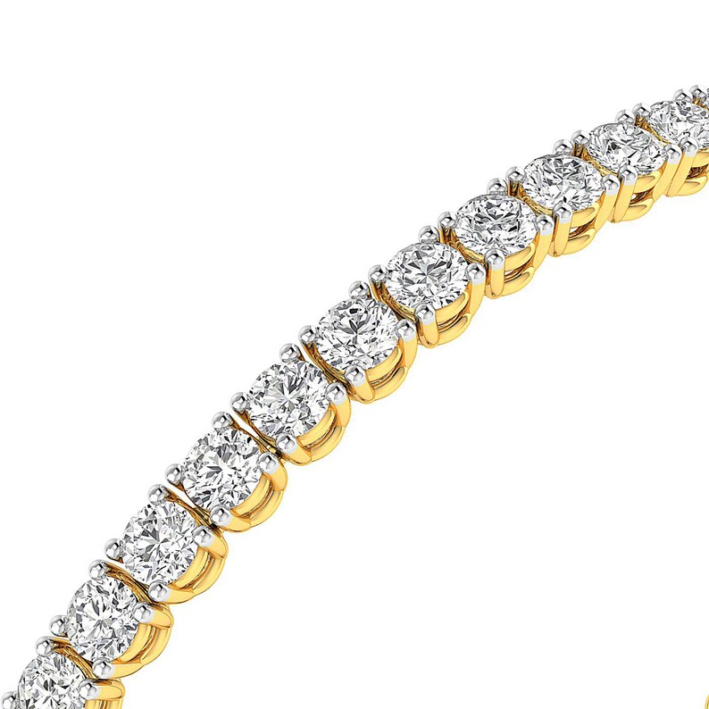 Puede incluir: Una pulsera de tenis dorada con diamantes redondos y transparentes engastados en garras individuales. La pulsera se muestra sobre un fondo blanco, resaltando el brillo de las piedras preciosas. Una pieza de joyer&iacute;a cl&aacute;sica.